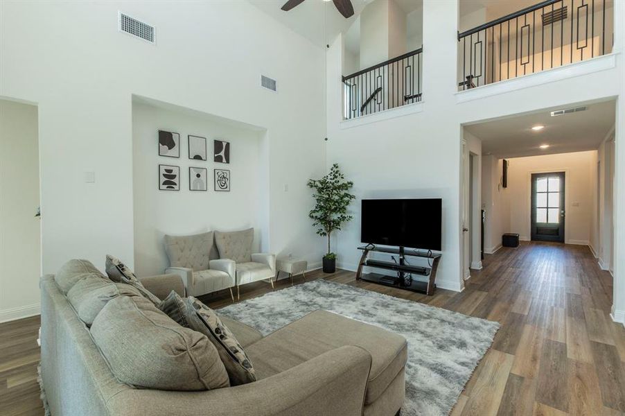 Vaulted ceilings enhance this open living space featuring wood-finish flooring, a contemporary staircase with black metal railings, and recessed lighting