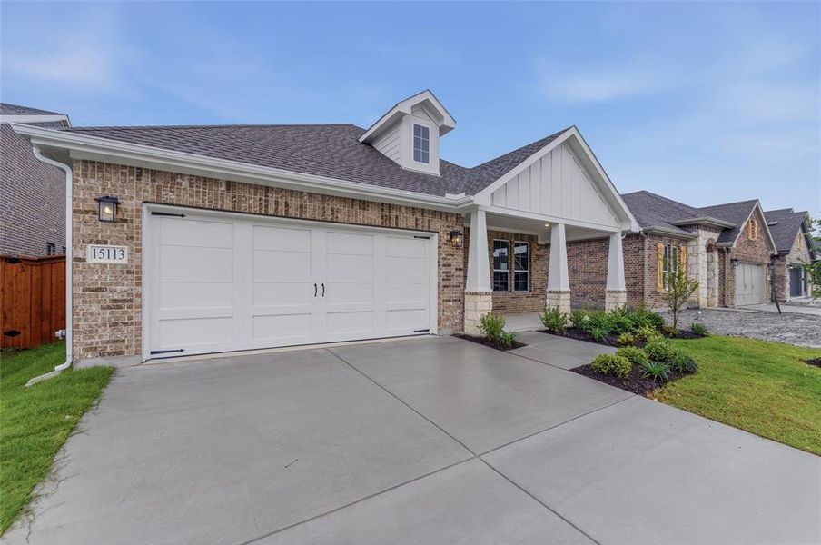 Brick and stone exterior featuring a two-car garage with a concrete driveway