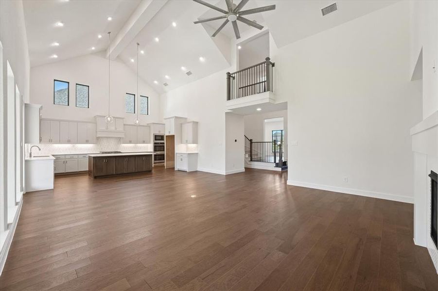 Unfurnished living room featuring beamed ceiling, a fireplace, dark wood-style flooring, high vaulted ceiling, and recessed lighting