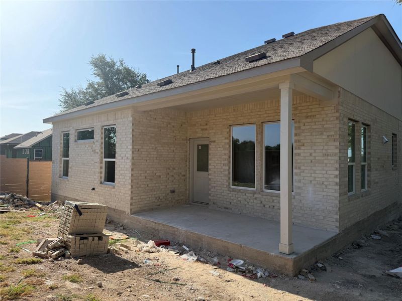Light brick construction highlights the covered rear patio under a classic gabled roofline.