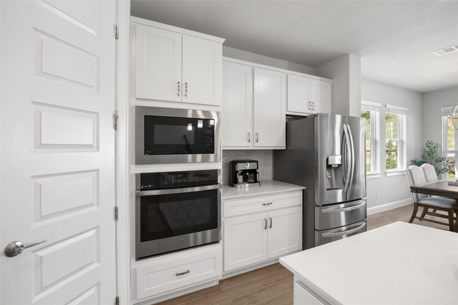 Kitchen featuring stainless steel appliances, light wood-style flooring, light countertops, and white cabinetry