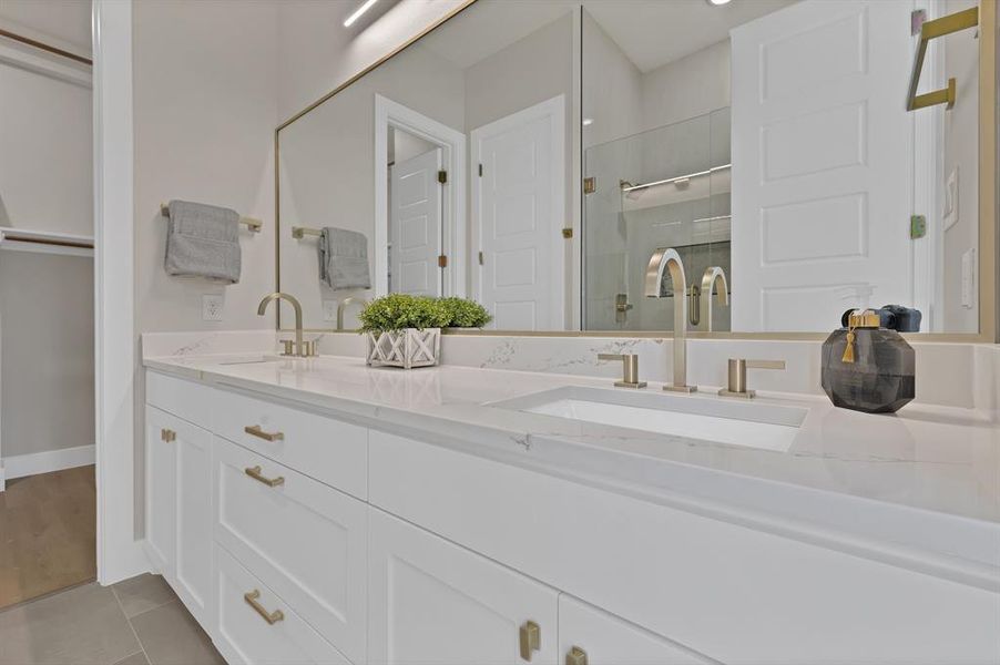 Full bath featuring double vanity, a stall shower, tile patterned flooring, and baseboards Full bath featuring double vanity, a stall shower, tile patterned flooring, and baseboards