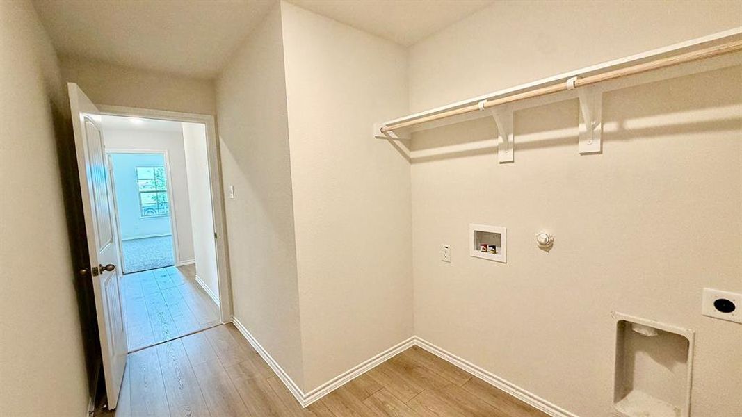 Dedicated laundry area featuring a wood-finish rod and shelving