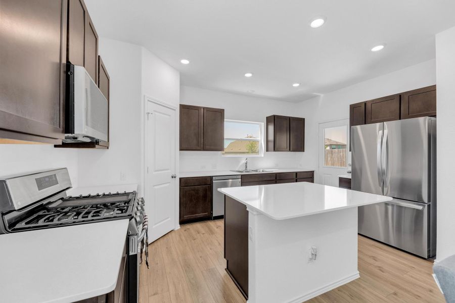 Kitchen with stainless steel appliances, light wood-style flooring, a sink, and dark brown cabinets