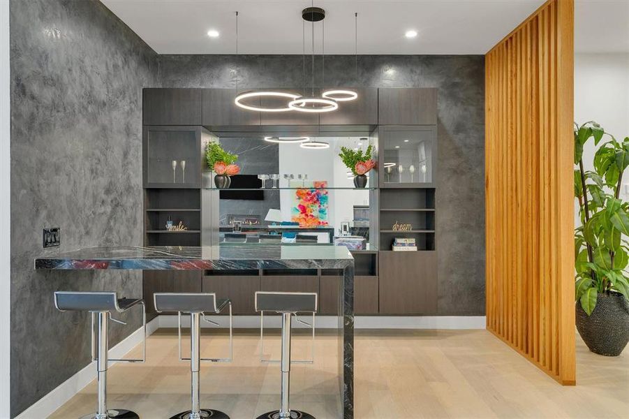 Kitchen featuring modern cabinets, pendant lighting, a breakfast bar area, and open shelves Kitchen featuring modern cabinets, pendant lighting, a breakfast bar area, and open shelves