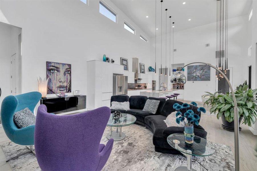 Living room with light wood-type flooring, a high ceiling, and recessed lighting