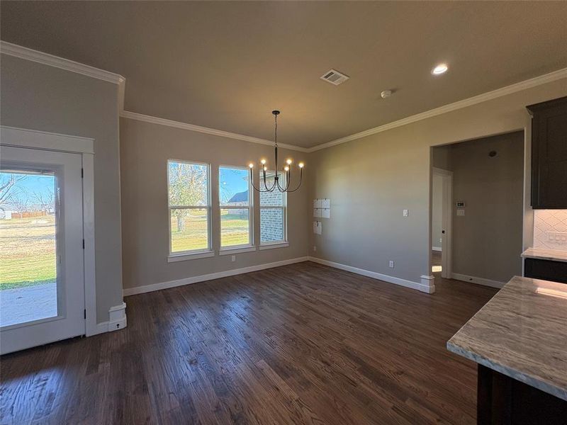 Unfurnished dining area with a chandelier, crown molding, and dark wood-type flooring