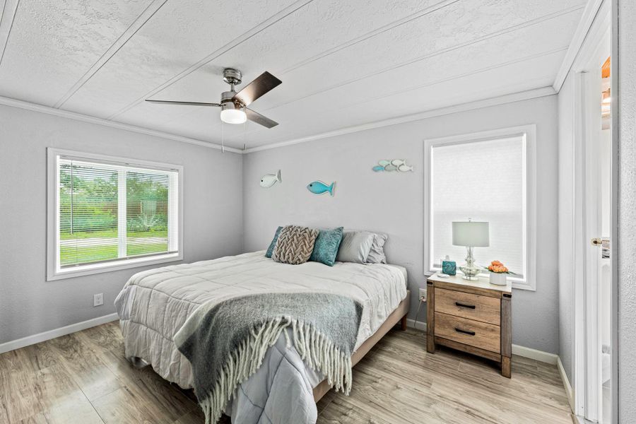 Room featuring wood-finish flooring, a ceiling fan with integrated lighting, and light gray painted walls