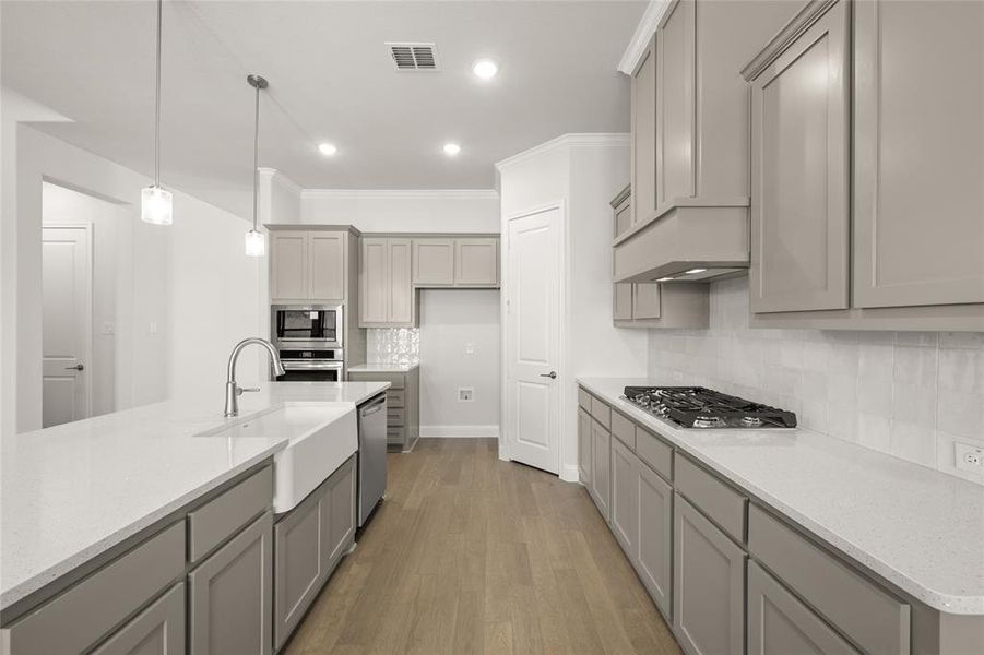 Kitchen with stainless steel appliances, a sink, gray cabinets, light wood-style flooring, and decorative backsplash Kitchen with stainless steel appliances, a sink, gray cabinets, light wood-style flooring, and decorative backsplash