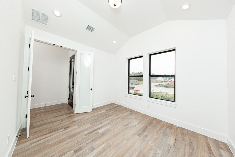 Tucked peacefully in the front of the home is this handsome home office. It features tile flooring, large windows, cathedral ceilings, custom paint, and gorgeous French doors for added privacy!