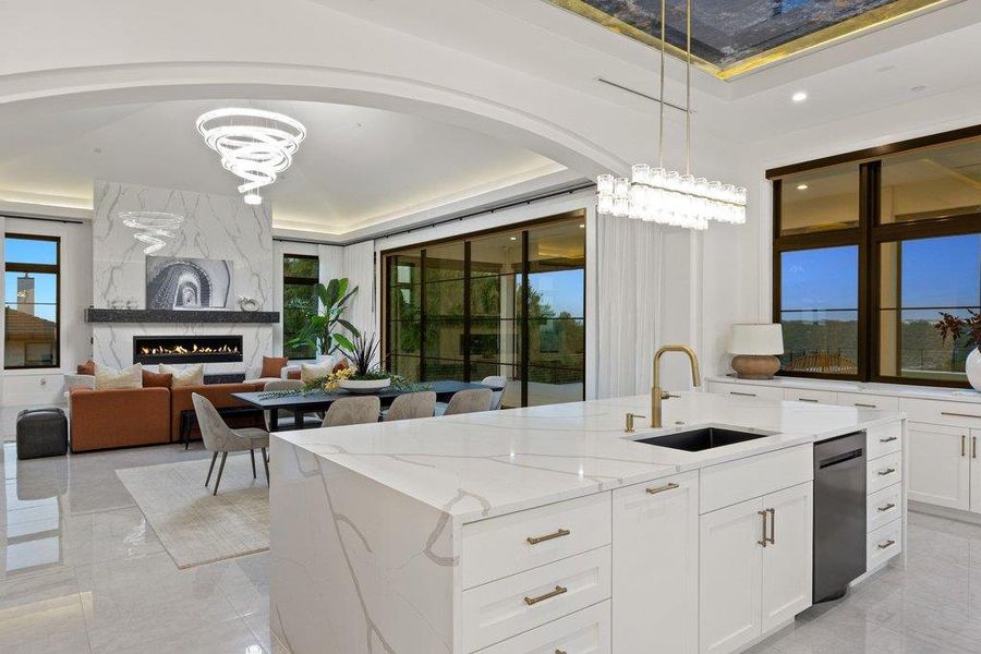 A refined open-concept kitchen and living area feature a striking fireplace and expansive windows.