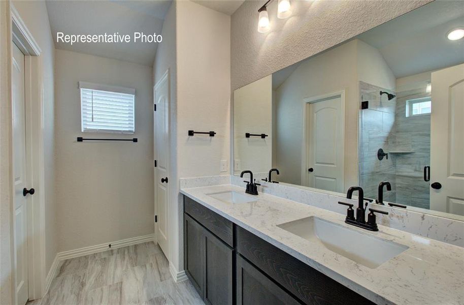 Bathroom featuring vanity, a shower with door, a wealth of natural light, and vaulted ceiling