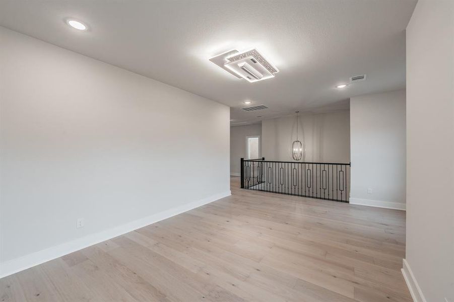 Spare room featuring light wood-type flooring, recessed lighting, and a chandelier
