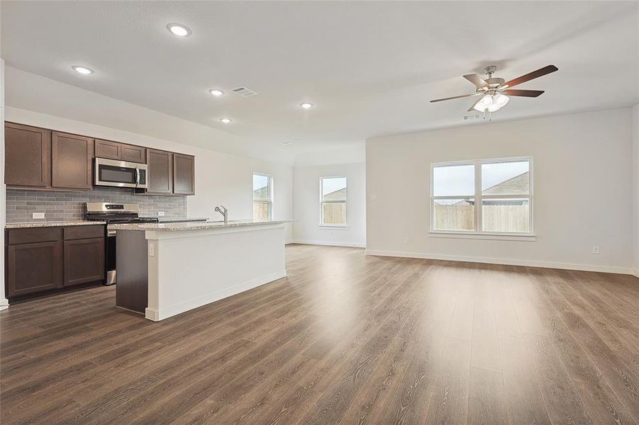 Kitchen featuring a kitchen island with sink, appliances with stainless steel finishes, dark hardwood / wood-style floors, and tasteful backsplash