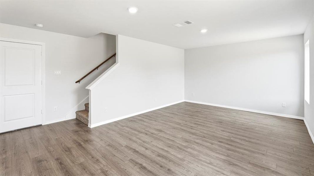 Unfurnished living room featuring dark wood-type flooring and recessed lighting