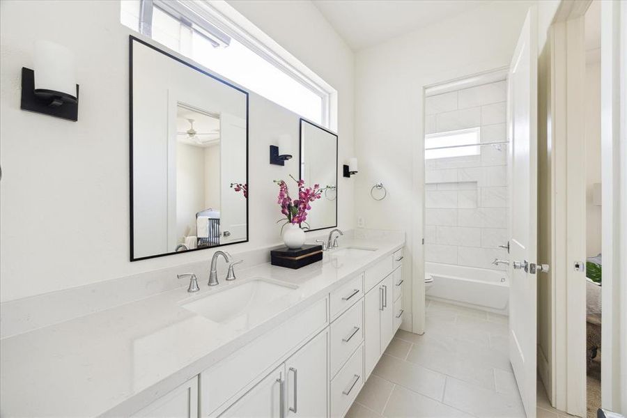 Well Organized - The Guest Bath features a double vanity with quartz countertop, under-mount sinks framed mirror flanked by a pair of wall sconces. Private toilet and bath.