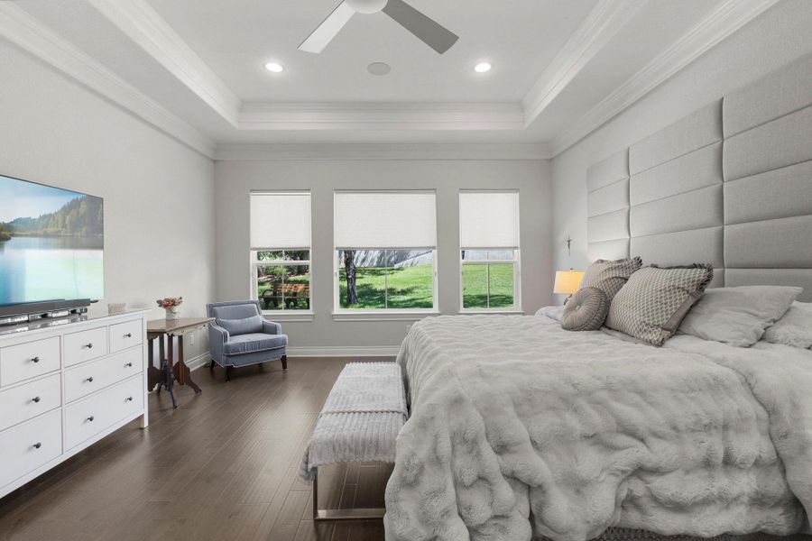 Hardwood floors and a tray ceiling define this elegant sleeping chamber, offering serene views of the green landscape.