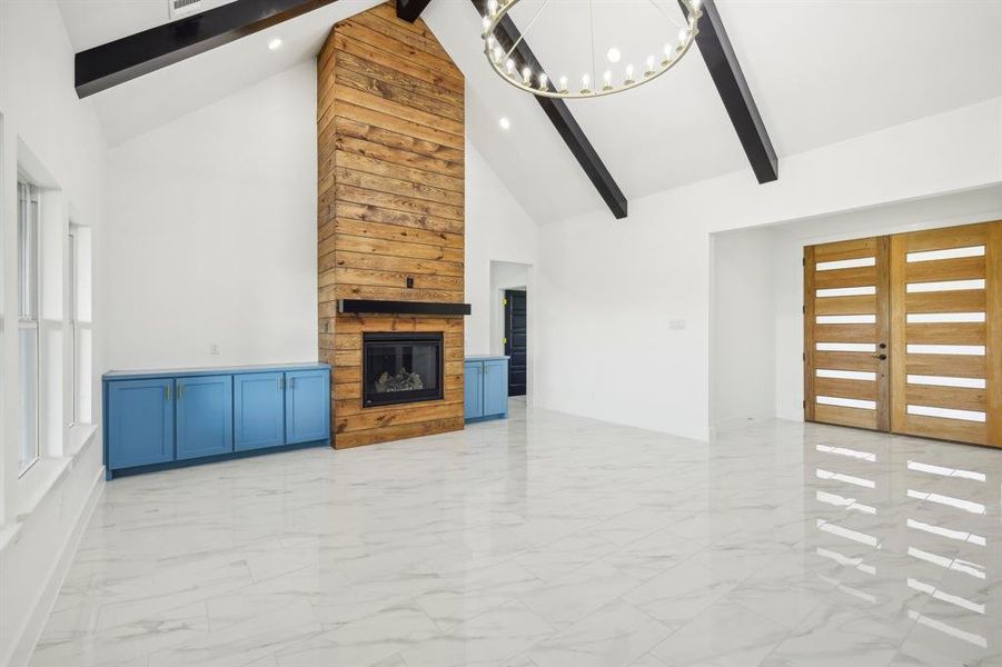 Unfurnished living room with french doors, beamed ceiling, high vaulted ceiling, a chandelier, and a fireplace