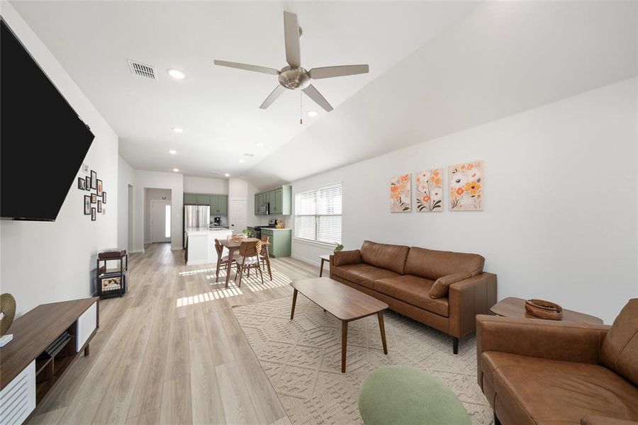 Living room with ceiling fan, lofted ceiling, and light wood-type flooring