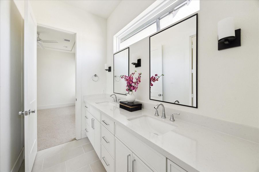 Well Organized - The Guest Bath features a double vanity with quartz countertop, under-mount sinks framed mirror flanked by a pair of wall sconces. Private toilet and bath. Well Organized - The Guest Bath features a double vanity with quartz countertop, under-mount sinks framed mirror flanked by a pair of wall sconces. Private toilet and bath.