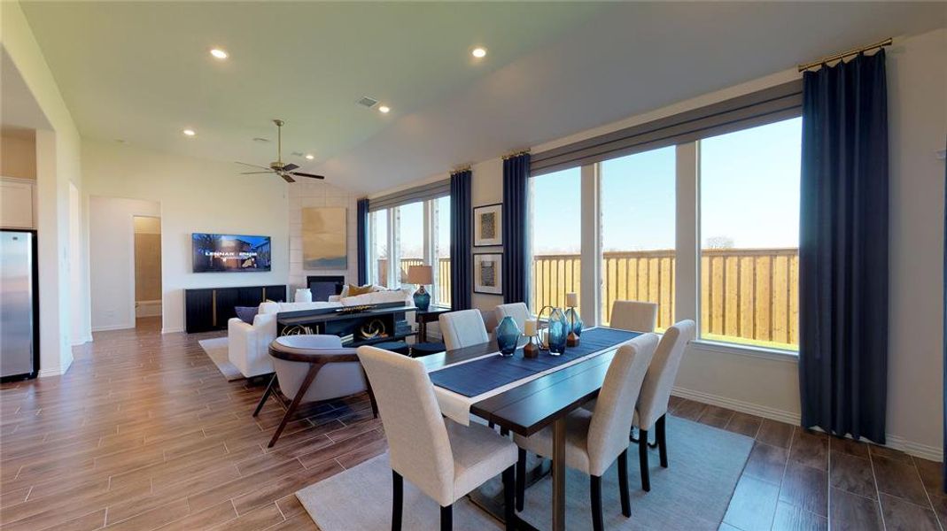 Dining space with wood tiled floors, recessed lighting, lofted ceiling, a fireplace, and a ceiling fan