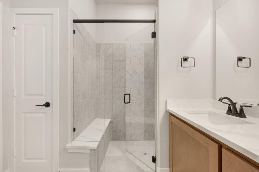 Bathroom with glass-enclosed tile shower with bench seat and wood vanity with white countertop Bathroom with glass-enclosed tile shower with bench seat and wood vanity with white countertop