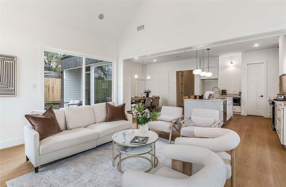 Living room with light wood-style floors, high vaulted ceiling, and recessed lighting