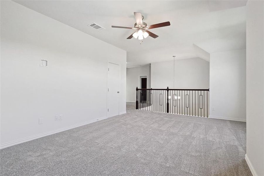 Carpeted spare room with ceiling fan and lofted ceiling