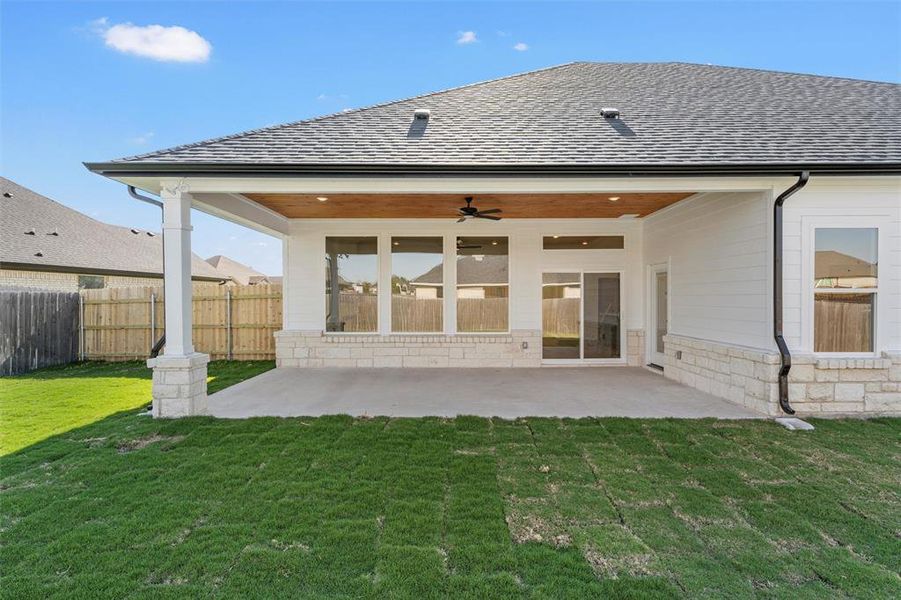 Rear view of property with a shingled roof, a patio area, ceiling fan, and a fenced backyard