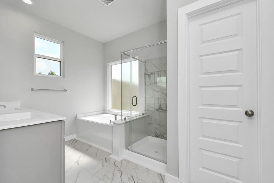 Immerse yourself in a luxurious retreat within the confines of your main bathroom. Enjoy the roomy walk-in shower encased in stylish tile, take a moment to unwind in a separate garden tub embellished with custom details. Sample photo of completed home with similar floor plan. Actual colors and selections may vary.