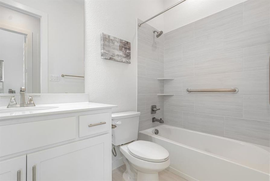 Bathroom featuring shower / bath combination, vanity, and a textured wall Bathroom featuring shower / bath combination, vanity, and a textured wall