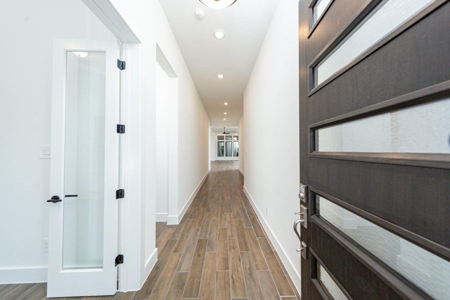 An inviting entrance opens up to an open-concept layout, seamlessly connecting the entry to the living areas with durable wood look tile flooring and striking architectural details.