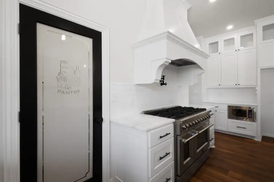 Kitchen featuring glass insert cabinets, white cabinets, and stainless steel appliances