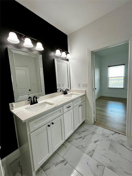 Full bathroom featuring double vanity and light marble finish floors Full bathroom featuring double vanity and light marble finish floors