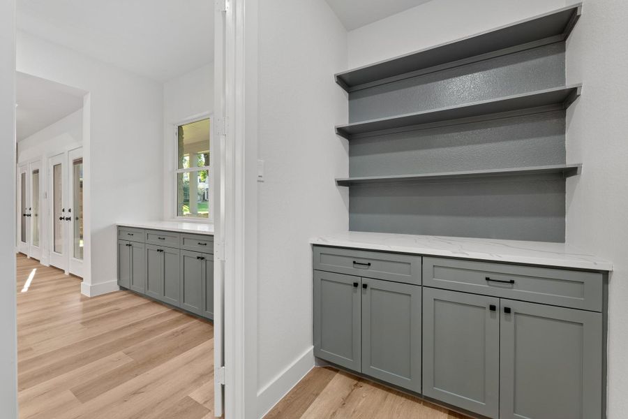 Luxurious butler's pantry featuring custom cabinets, elegant shelving, and a sleek quartz countertop. Luxurious butler's pantry featuring custom cabinets, elegant shelving, and a sleek quartz countertop.