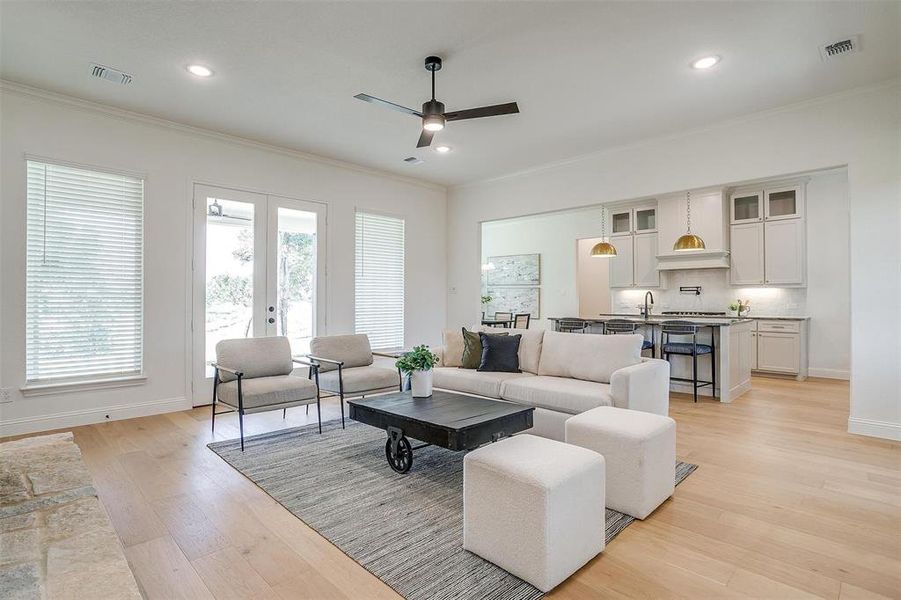 Living room with light hardwood / wood-style flooring, ornamental molding, and ceiling fan