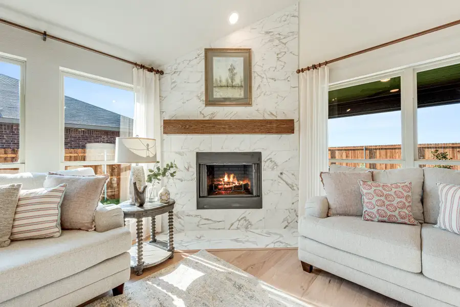 Living room with marble tile fireplace, wood mantel, two sofas, and hardwood floors