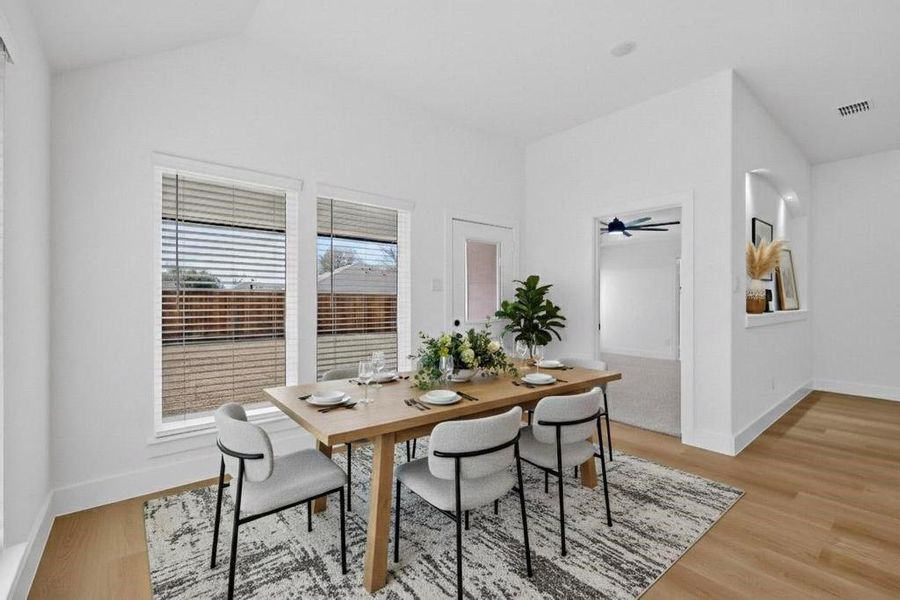 Dining space featuring light wood-style floors, a ceiling fan, and vaulted ceiling