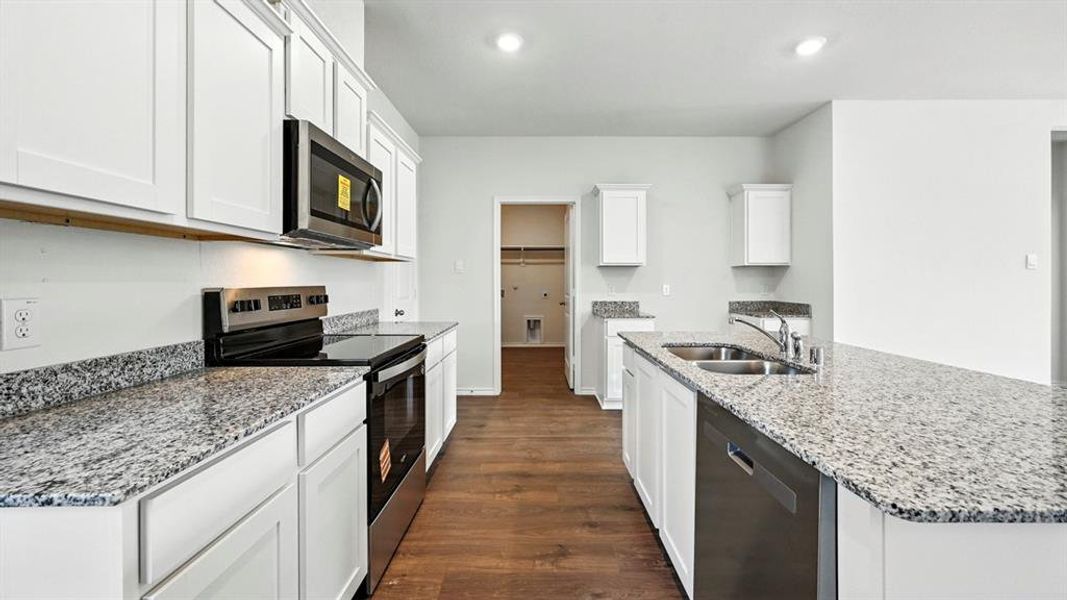 Kitchen featuring white cabinetry, granite countertops, wood-finish flooring, stainless steel appliances, and a double basin sink