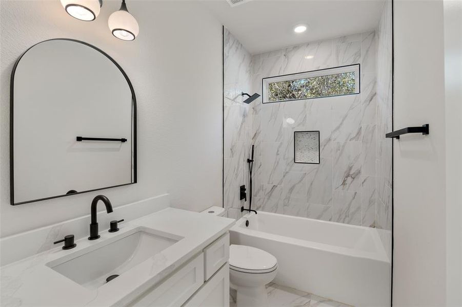 Full bathroom featuring vanity, toilet, and tiled shower / bath combo