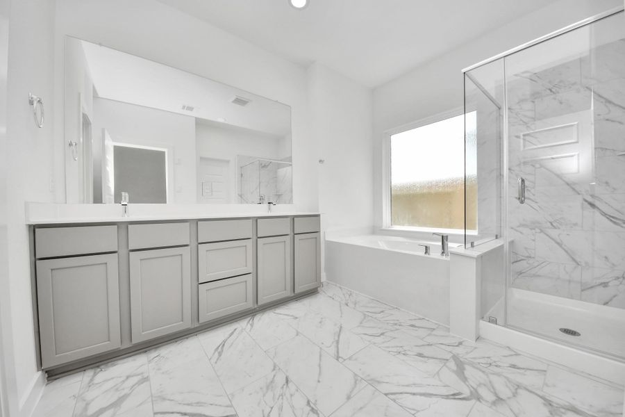Escape to a spa-like oasis in this primary bathroom. Enjoy a walk-in shower with tile surround, a separate garden tub with custom detailing, and an elegant vanity featuring light countertops, modern hardware, and beautiful recessed lights. Experience luxury and relaxation in every detail. Sample photo of completed home with similar floor plan. Actual colors and selections may vary. Escape to a spa-like oasis in this primary bathroom. Enjoy a walk-in shower with tile surround, a separate garden tub with custom detailing, and an elegant vanity featuring light countertops, modern hardware, and beautiful recessed lights. Experience luxury and relaxation in every detail. Sample photo of completed home with similar floor plan. Actual colors and selections may vary.