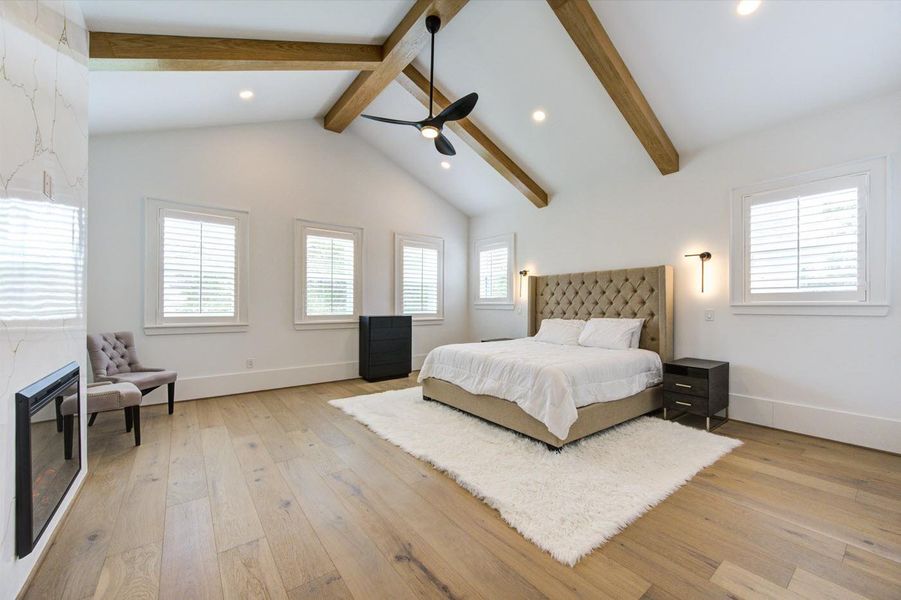 Breathtaking primary bedroom featuring cathedral ceiling accented with beams and Plantation Window Shutters.