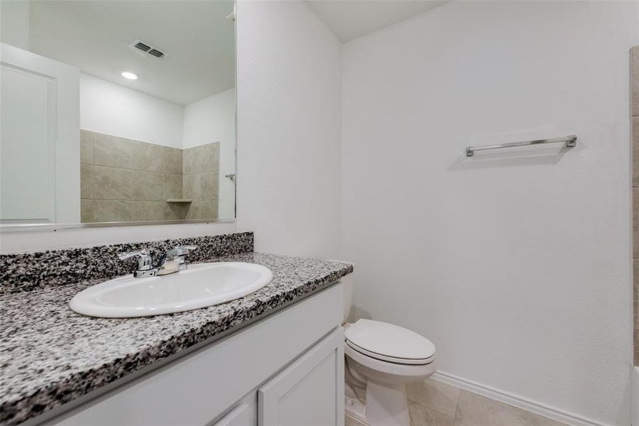 Bathroom featuring toilet, vanity, tile patterned flooring, and a shower