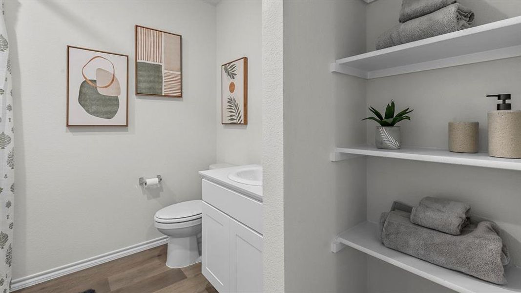 This bathroom features light-colored walls, wood-look flooring, and a white vanity with a sink