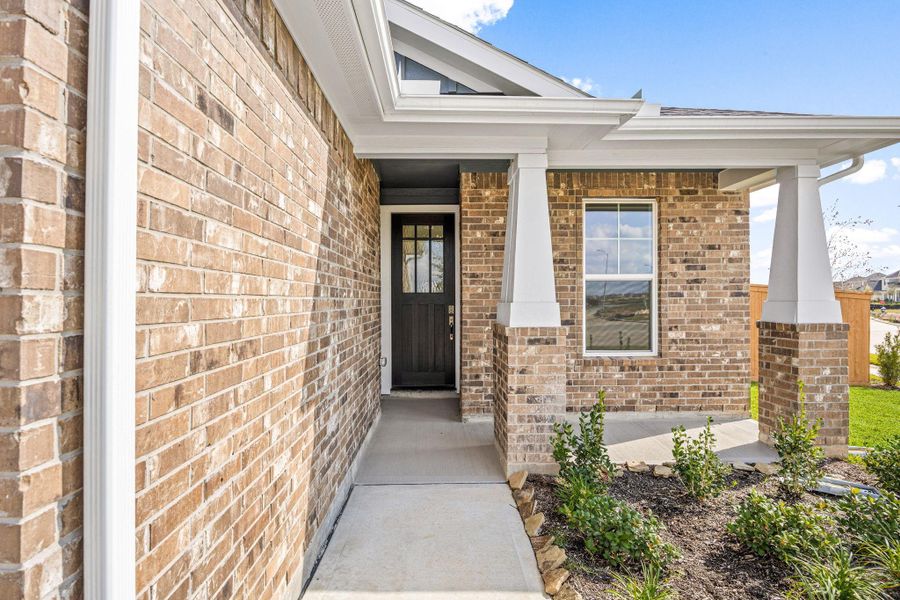 A charming, covered front porch and inviting entryway with durable brick exterior detailing. The house is a single-story property and includes gutters on the front. The front door features glass panels in the upper portion and mullions. A charming, covered front porch and inviting entryway with durable brick exterior detailing. The house is a single-story property and includes gutters on the front. The front door features glass panels in the upper portion and mullions.