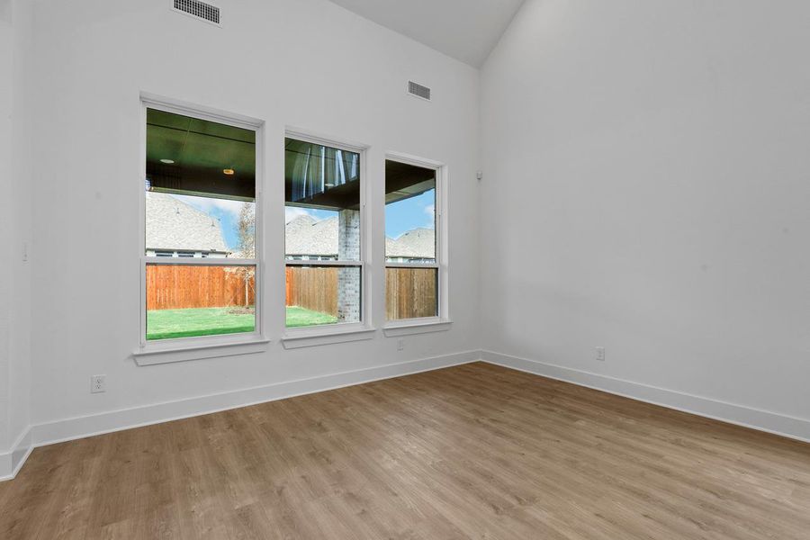 Spare room with visible vents, baseboards, wood finished floors, and vaulted ceiling Spare room with visible vents, baseboards, wood finished floors, and vaulted ceiling