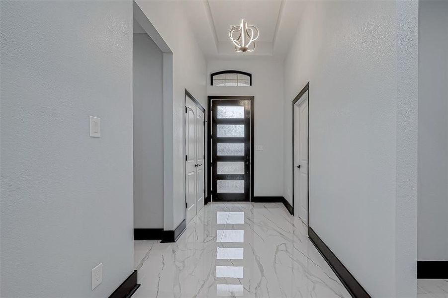 Step into the grand entrance featuring sleek modern tall door and a spacious double-door coat closet.