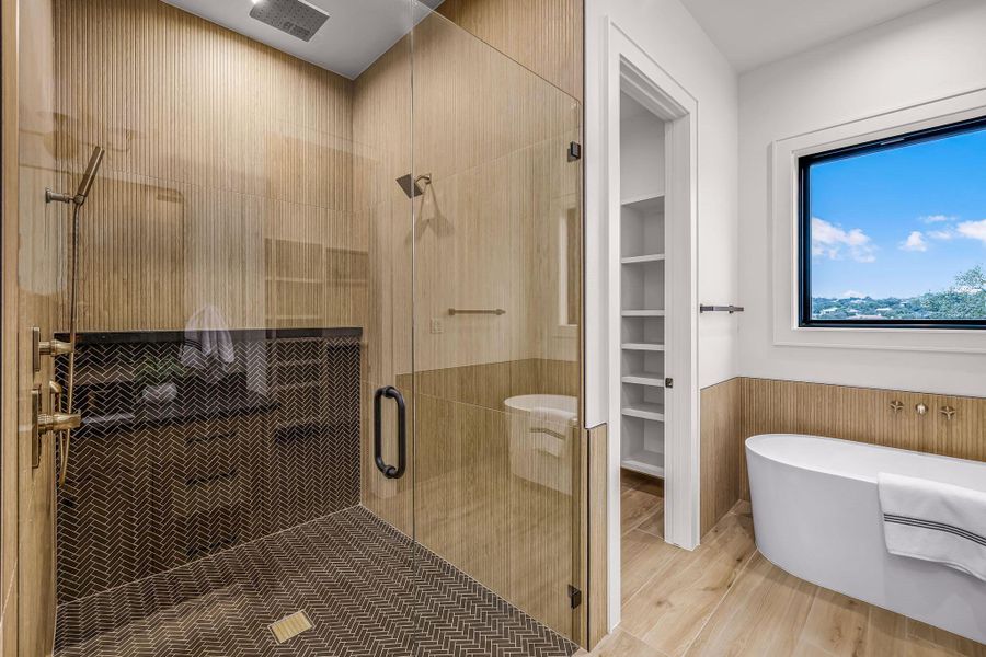 Bathroom with a stall shower, a freestanding tub, a spacious closet, and wood finished floors