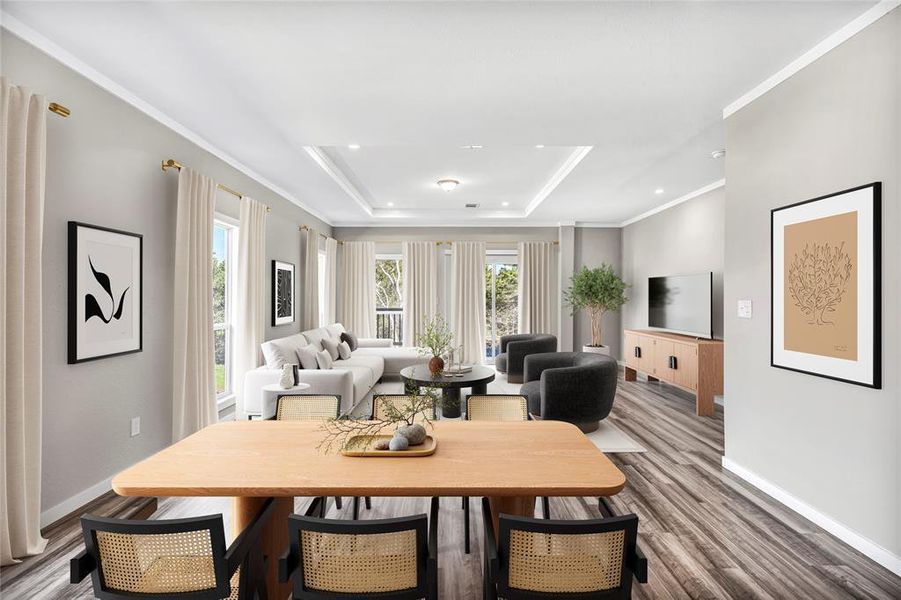 Dining space with ornamental molding, a raised ceiling, and wood finished floors