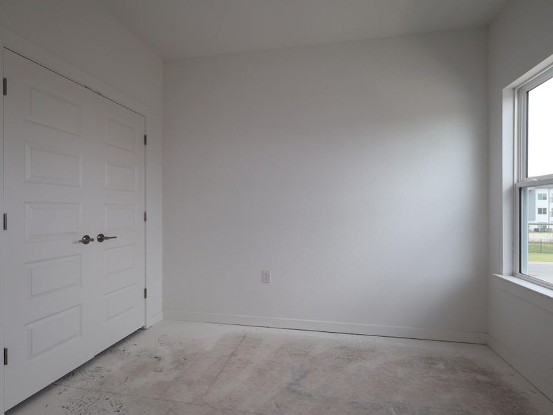 A well-lit room awaits your personal touch, featuring a large window for natural illumination.